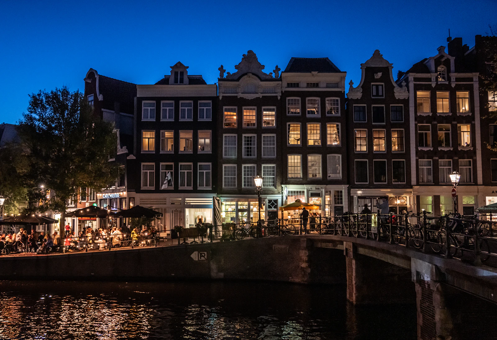 Amsterdam canal houses at dusk with illuminated windows
